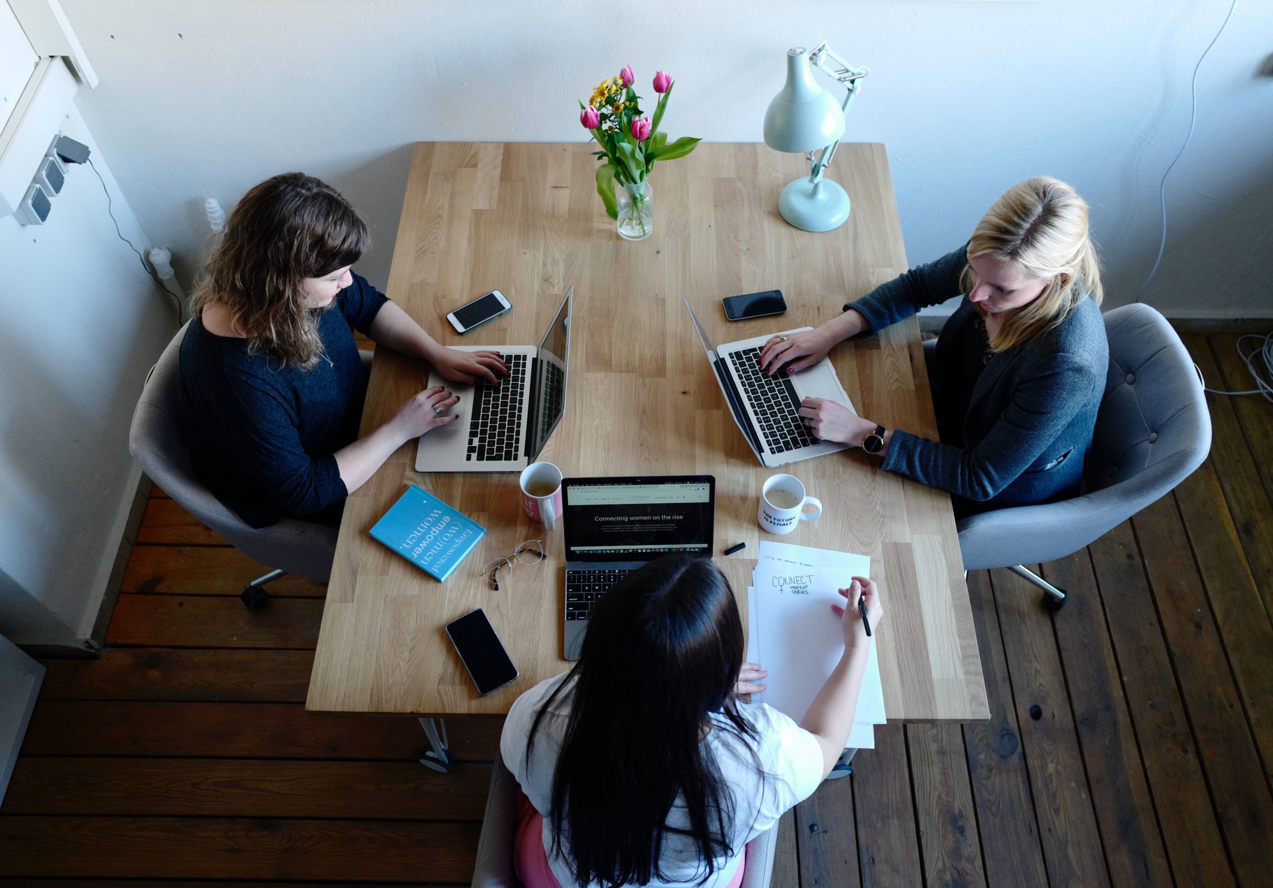 Three people sitting at a desk working on laptops