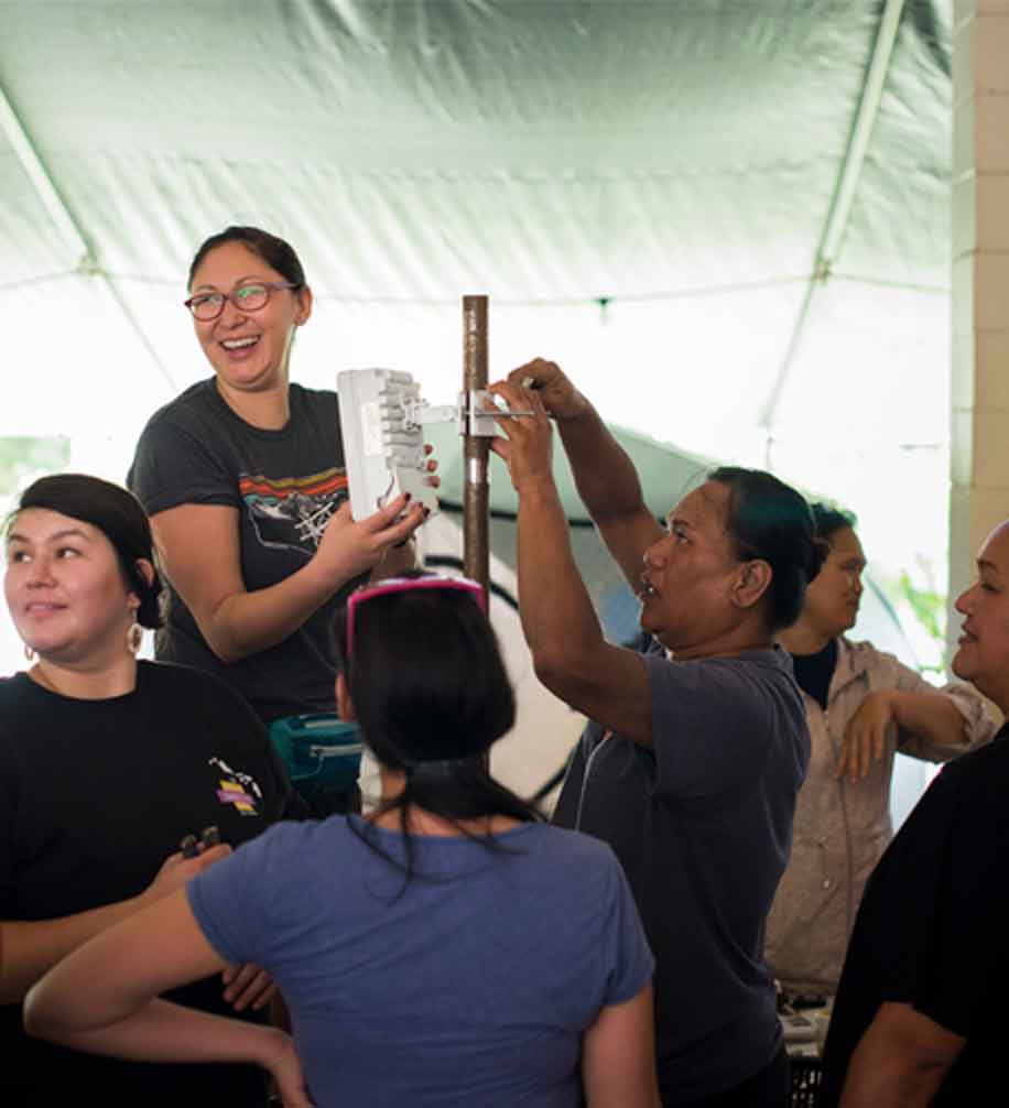 a group of women installing an antenna under tent