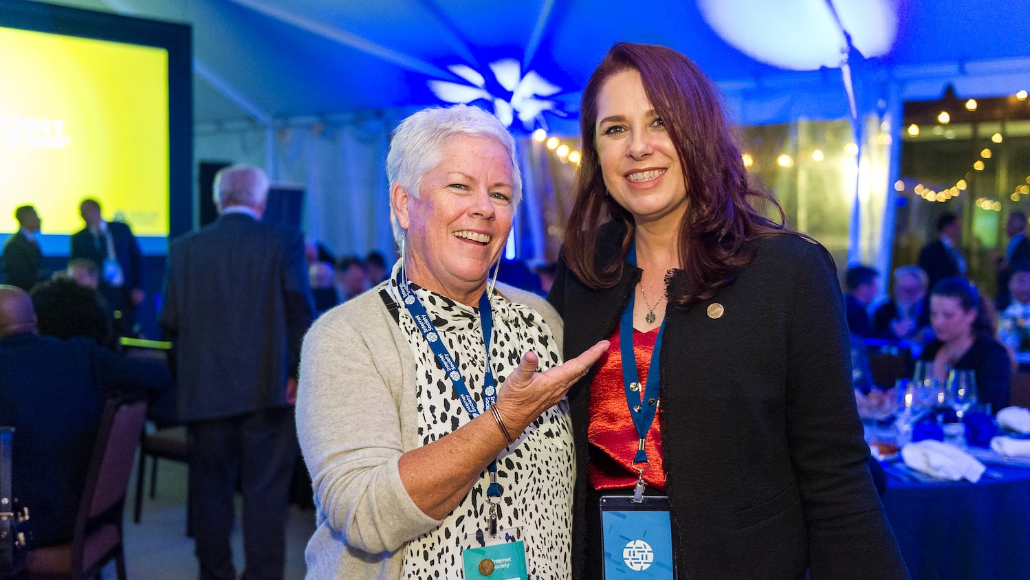 two women smiling while one is pointing to another with a hand