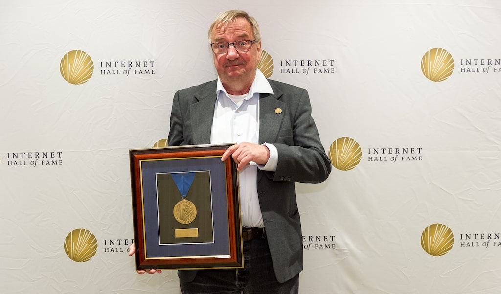 a man posing for a photo holding a plaque with a medal